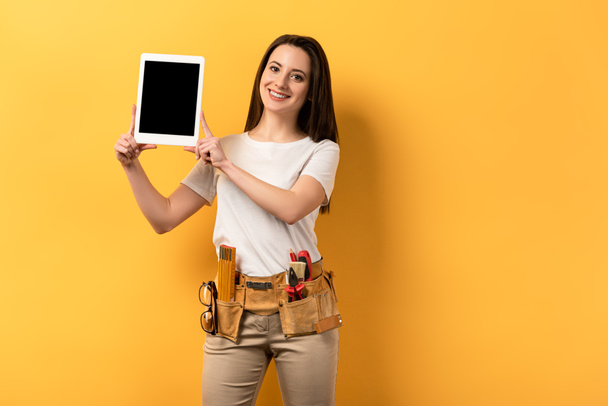 femme à tout faire souriante tenant tablette numérique avec espace de copie sur fond jaune
 - Photo, image