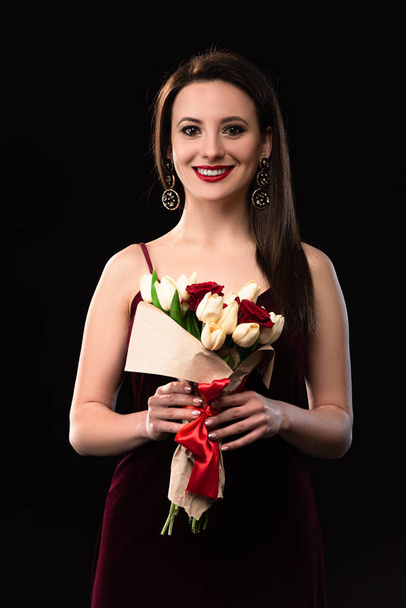 smiling woman in dress holding bouquet isolated on black - Fotoğraf, Görsel