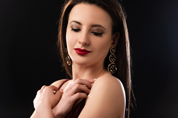 aantrekkelijke vrouw met oorbellen kijken neer op zwarte achtergrond  - Foto, afbeelding
