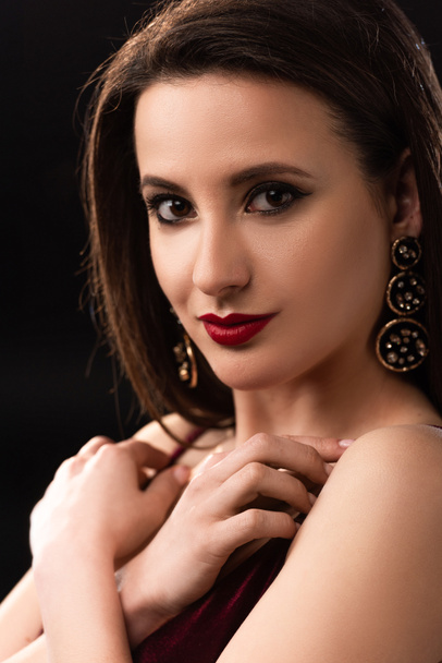 attractive woman with earrings looking at camera isolated on black - Photo, Image