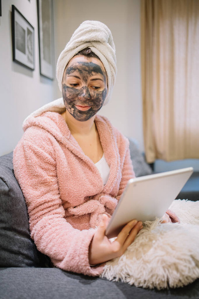 Lady with charcoal mask looking a tablet - Foto, immagini