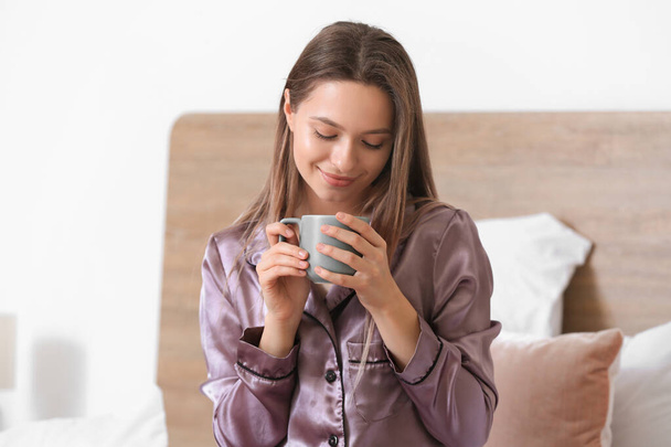 Πρωινό της όμορφης νεαρής γυναίκας πίνοντας καφέ στην κρεβατοκάμαρα - Φωτογραφία, εικόνα