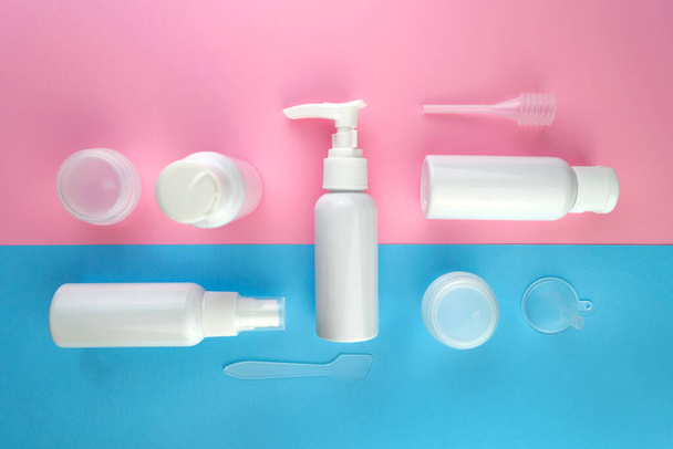 Travel size cosmetic flat lay. Top view beauty composition on pink and blue background. Cream sample bottle vacation airplane kit - Foto, imagen