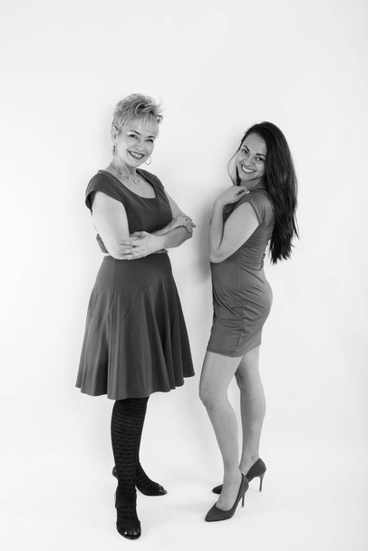 Full body shot of happy senior Asian woman and young beautiful woman smiling while posing with arms crossed against white background - Foto, imagen