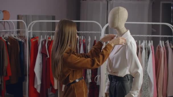 Kaunis nainen valitsee vaatteita merkkituotteella varustetussa vaatehuoneessa
 - Materiaali, video