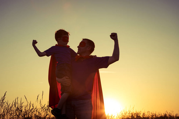 Father and son playing superhero at the sunset time. People having fun outdoors. Concept of friendly family. - Foto, Bild