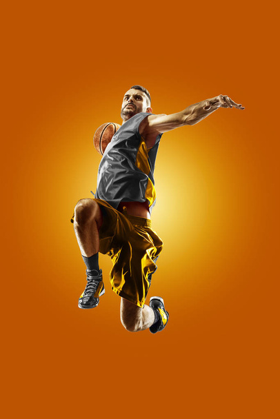 bright professional basketball player on an orange background - Fotó, kép