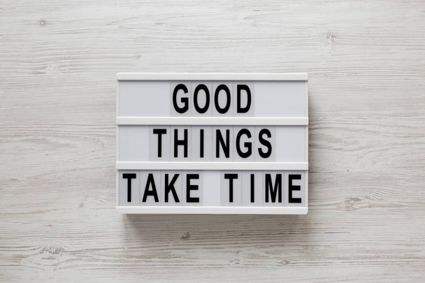 'Good things take time' words on a modern board on a white wooden background, top view. Overhead, from above, flat lay.  - Fotó, kép