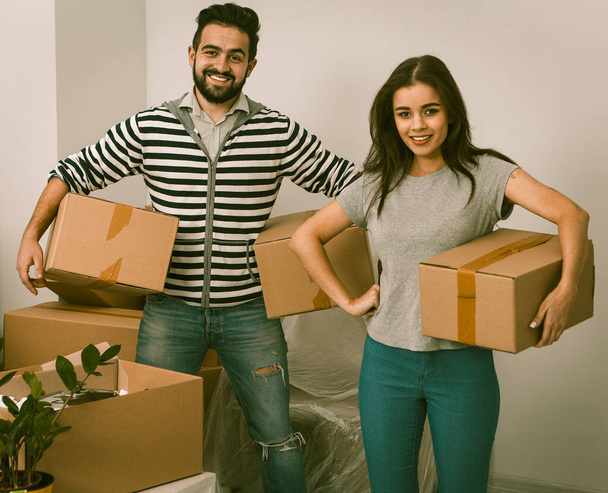Heureux mari et femme portant des boîtes dans leur nouvelle maison
. - Photo, image