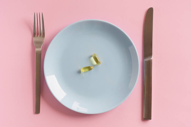 Лекарства на белой тарелке с вилкой и ножом
 - Фото, изображение