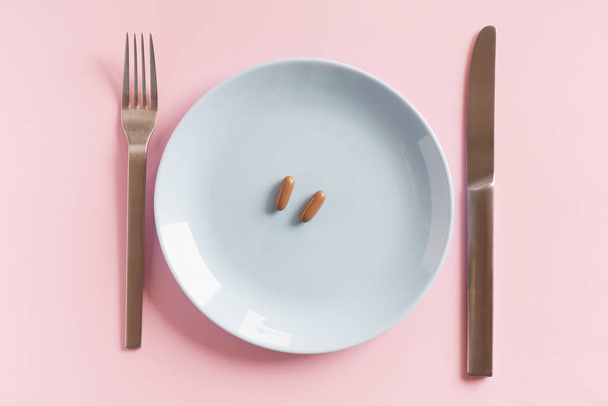 Лекарства на белой тарелке с вилкой и ножом
 - Фото, изображение