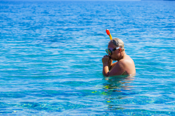Şnorkel ekipmanlı bir dalgıç okyanus suyunda maske tüpü kullanıyor. Yaz tatili yüzme eğlence konsepti. - Fotoğraf, Görsel