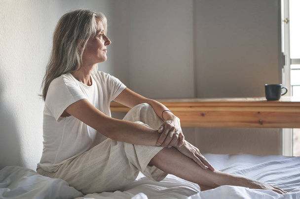 mature woman sitting on the bed in the morning - Foto, immagini