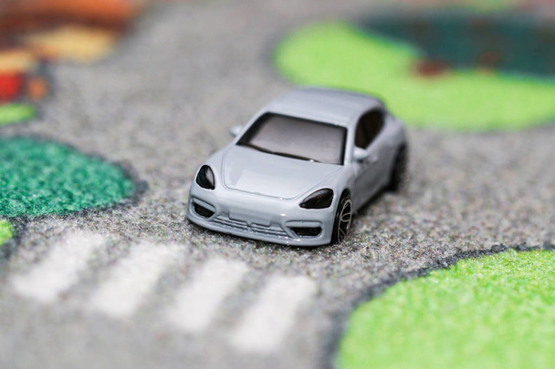 Spielzeugauto hat vor Zebrastreifen auf Autoteppichstraße angehalten - Foto, Bild