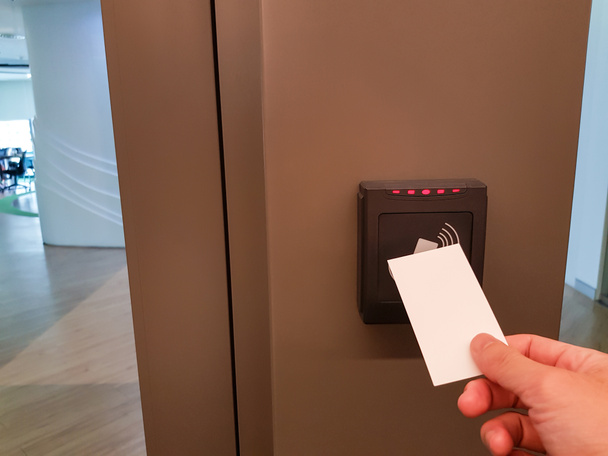 Muži se natahují, aby použili RFID kartu pro přístup do kancelářských prostor. V zabezpečení budovy pouze pro autorizovanou osobu - Fotografie, Obrázek