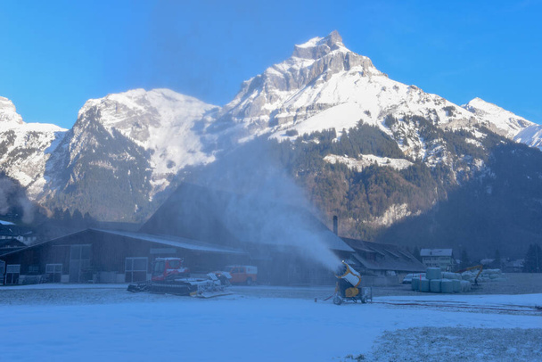 İsviçre Alplerinde Engelberg 'de kayak pistinde yapay kar püskürten kar makinesi. - Fotoğraf, Görsel
