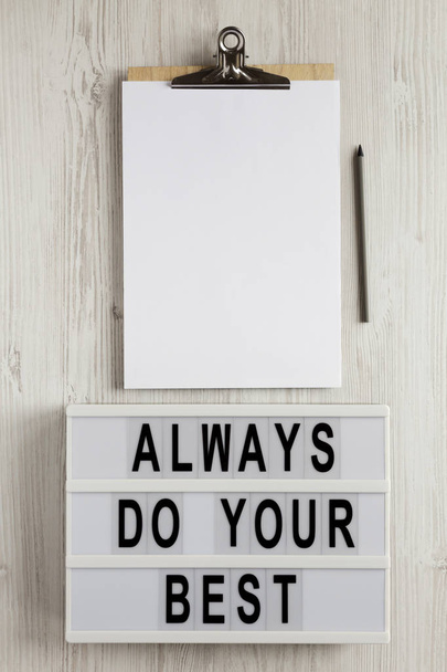 'Fai sempre del tuo meglio 'parole su una scatola luminosa, appunti con foglio di carta bianco su una superficie di legno bianco, vista dall'alto. Sopra, dall'alto, distesa piatta
.  - Foto, immagini
