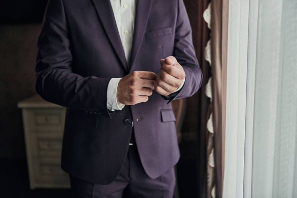 Podnikatel nosí bundu, mužské ruce zblízka nahoru, ženich se připravuje ráno před svatebním obřadem - Fotografie, Obrázek