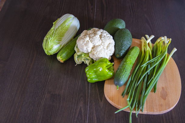Fresh vegetables on a black background. Avocado, onions, cucumbers, peppers, cauliflower and Chinese cabbage, salad, paprika. View from above. Free space for your text. - Photo, Image