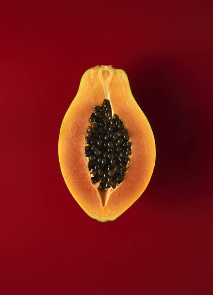 Нарізана папайя навпіл на червоному тлі
 - Фото, зображення