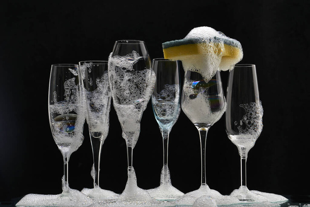ποτήρια σαμπάνιας με σφουγγάρι και σαπουνόφουσκες σε μαύρο φόντο - Φωτογραφία, εικόνα