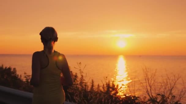 Vue arrière de Silhouette d'une femme faisant du jogging dans les rayons du soleil couchant
. - Séquence, vidéo