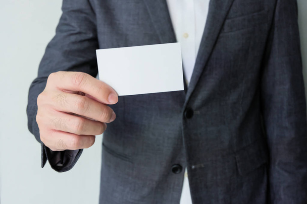 Männer Geschäftsmann in grauem Anzug und weißem Hemd mit weißen Visitenkarten-Attrappen, auf denen Name und Text stehen. Werbung für Geschäftskonzept, Kontaktdetails. - Foto, Bild