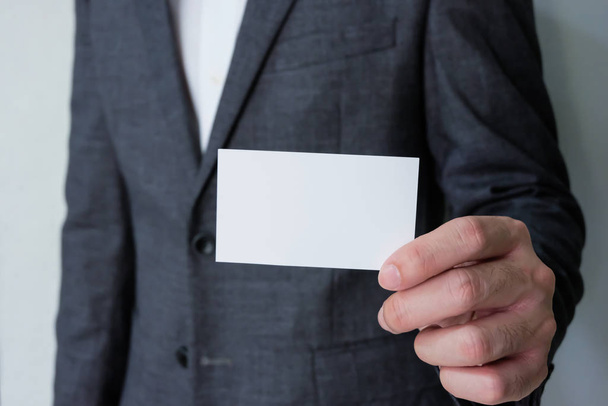 Männer Geschäftsmann in grauem Anzug und weißem Hemd mit weißen Visitenkarten-Attrappen, auf denen Name und Text stehen. Werbung für Geschäftskonzept, Kontaktdetails. - Foto, Bild