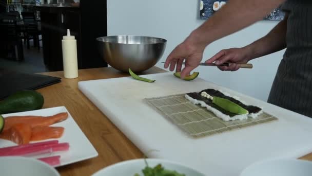 Sushi master preparing fresh and tasty sushi rolls in Japanese restaurant. Concept: Rolling a sushi roll on bamboo mat.Sushi making process, cutting ingredients - Imágenes, Vídeo