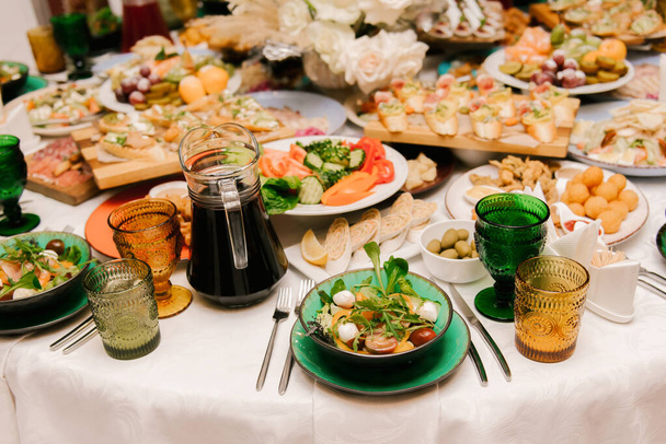 The round white table is filled with a large amount of food and various snacks in a luxurious interior, beautiful serving of the holiday table - Photo, Image