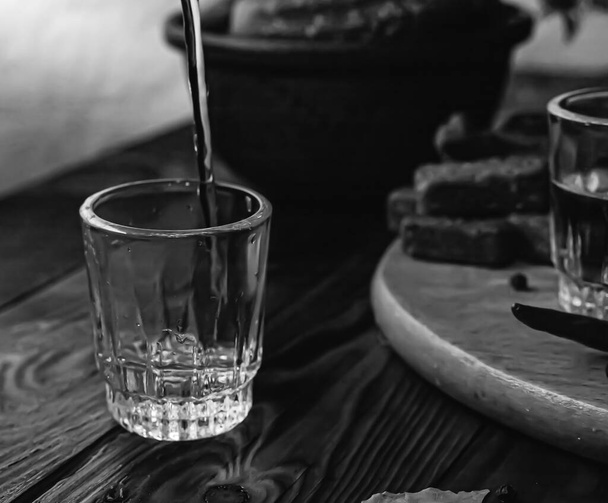 Bebida tradicional vodka en vasos, con un aperitivo en forma de embutidos y tocino, pepinos, conservación. Mesa nacional festiva rusa
. - Foto, imagen