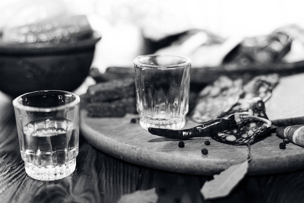 Bevanda vodka tradizionale in occhiali, con uno spuntino nella forma di salumi e pancetta, cetrioli, conservazione. Tavolo nazionale festivo russo
. - Foto, immagini