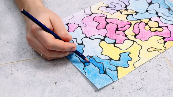 Der Mensch zeichnet ein abstraktes imaginäres Bild mit einem Bleistift und dekoriert es mit verschiedenen Farben, ein psychologischer Test für das Unterbewusstsein - Foto, Bild