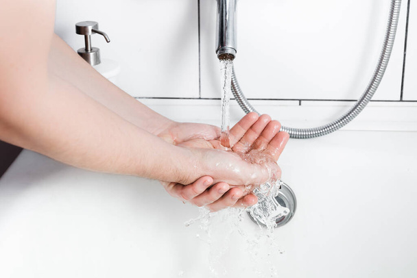 Een man die zeep wast in de badkamer. Persoonlijke hygiëne. Zuiver, gezuiverd kraanwater. Close-up. - Foto, afbeelding