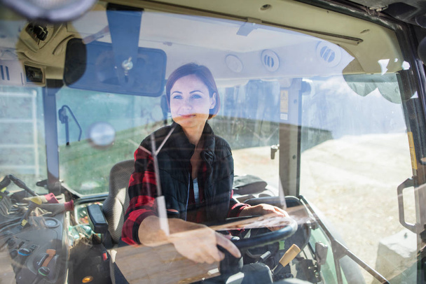 Woman worker riding tractor on diary farm, agriculture industry. - 写真・画像