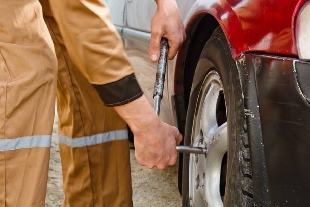 Auto mechanic man with electric screwdriver changing tire outside. Car service. Hands replace tires on wheels. Tire installation concept - Photo, image