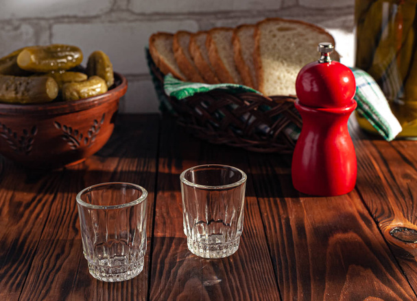 Traditional drink vodka in glasses, with a snack in the form of cold cuts and bacon, cucumbers, preservation. Russian festive national table. - Photo, Image