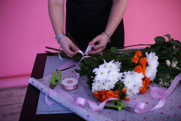 女の子の手は明るいピンクの背景に花の花束を収集します - 写真・画像