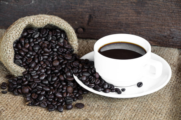 Coffee cup with coffee beans on burlap bag - Fotó, kép