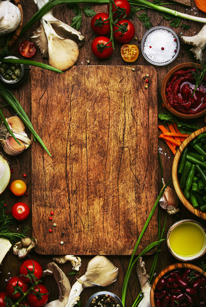 Food cooking background, ingredients for preparation vegan dishes, vegetables, roots, spices, mushrooms and herbs. Cutting board. Healthy food concept. Rustic wooden table, top view - Foto, imagen