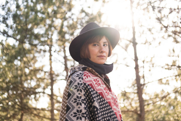 Yong hipster woman traveler in hat and poncho walking outdoors - Photo, Image