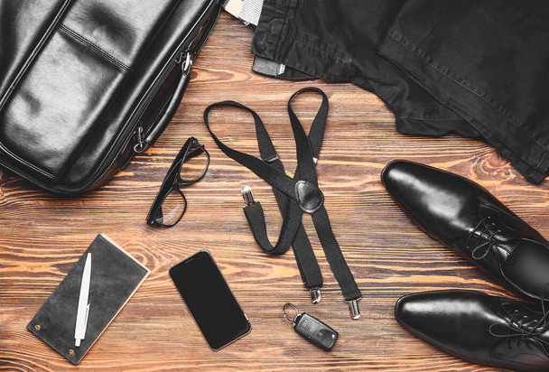 Roupas masculinas elegantes com acessórios e telefone celular em fundo de madeira
 - Foto, Imagem