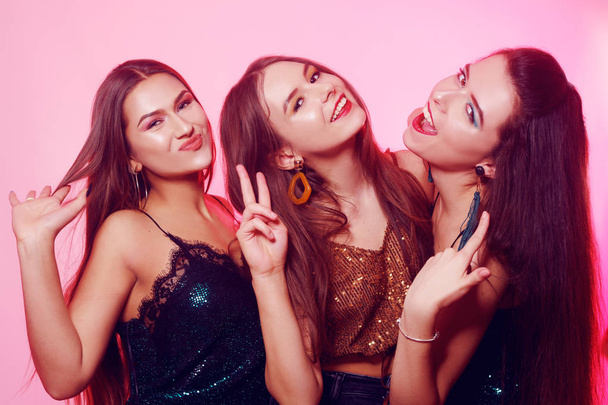 3 girls pose, make faces, show tongue. Girls in brilliant dresses with different colorful makeup. Three brunette girls dance and enjoy life. March 8, women's power, Women's Day. - Photo, Image
