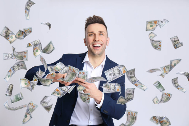 Щасливий молодий чоловік з грошима на світлому фоні
 - Фото, зображення