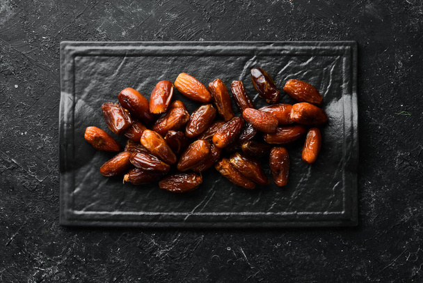 Dates. Delicious sweet turkish dates on black stone background. Top view. Free space for your text. - Foto, Imagem