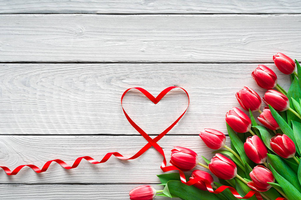 Červené tulipány a stuha ve tvaru srdce na dřevěném pozadí. Valentýn, Den matek, Všechno nejlepší, Svatba, Dámské svátky - Fotografie, Obrázek