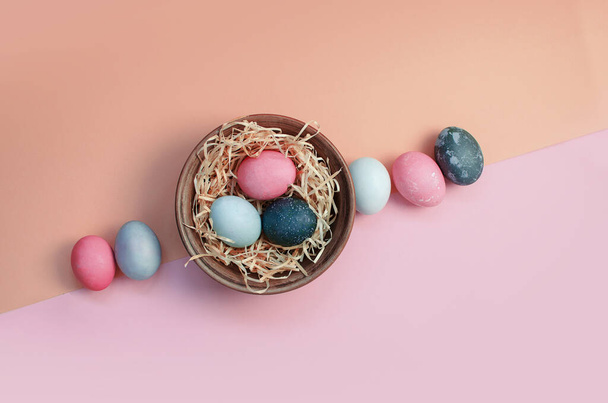 Velikonoční pozdrav pozadí s barvené mnohobarevné kuřecí vejce na slámě v talíři - Fotografie, Obrázek