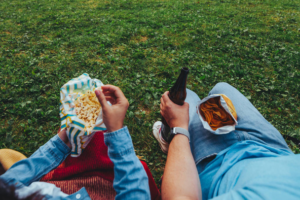 άποψη ζευγάρι σε εξωτερικούς χώρους τρώγοντας ποπ κορν πίνοντας μπύρα δεν πρόσωπα θερινή ώρα - Φωτογραφία, εικόνα