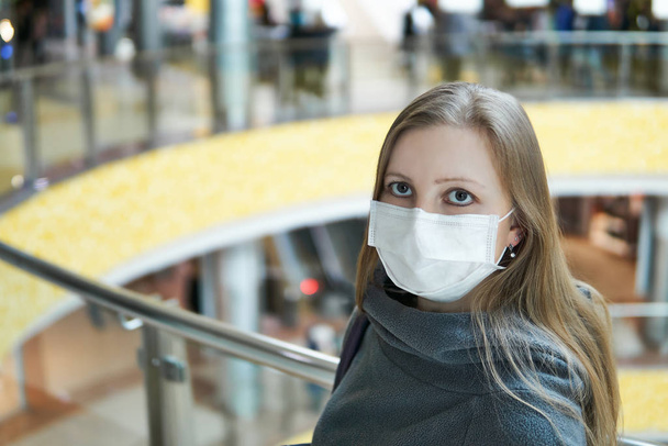 νεαρή λευκή γυναίκα με ιατρική μάσκα σε δημόσιο χώρο - Φωτογραφία, εικόνα