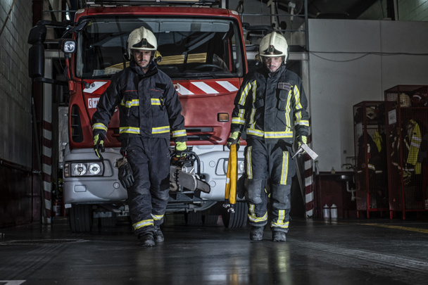 firemen leaving the station equipped and with the tools for the extinction of the fire - Foto, Bild
